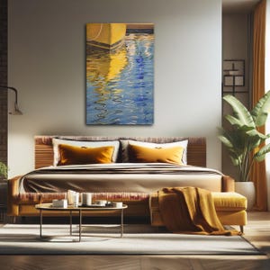 Op de afbeelding: Een schilderij van een gele boot met blauw water dat het zonlicht reflecteert. Het water rimpelt en de boot is gedeeltelijk ondergedompeld. Het schilderij is ingelijst en hangt aan een muur in een slaapkamer.