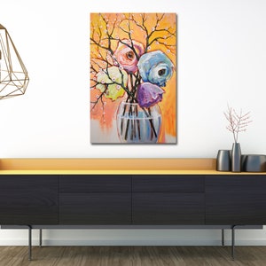 Op de afbeelding: Een schilderij van een boeket kleurrijke bloemen in een heldere glazen vaas. De bloemen zijn roze, blauw, paars en geel. De achtergrond is een warme oranje kleur met witte bloesems.