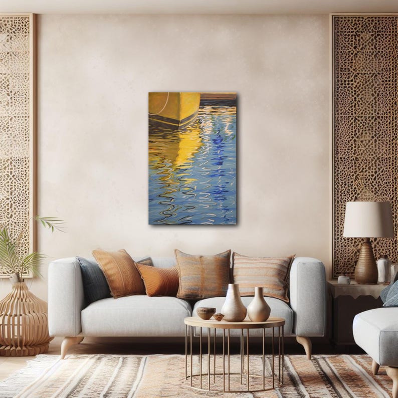Op de afbeelding: Een schilderij van een gele boot die wordt weerspiegeld in blauw water. Het water rimpelt en de reflectie is vervormd. Het schilderij is ingelijst en hangt aan een muur in een woonkamer.