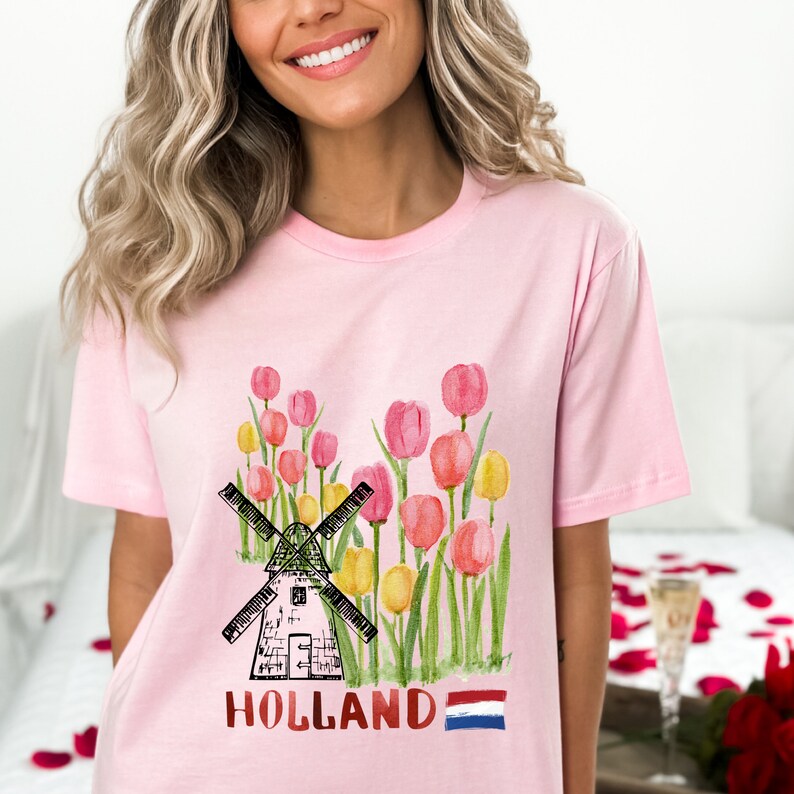 May include: Pink t-shirt featuring a watercolour illustration of a windmill, tulips, and the word "HOLLAND" with the Dutch flag.