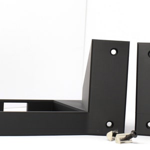 May include: Black, L-shaped brackets with pre-drilled holes, likely for mounting or support. Two brackets are upright, with a third lying flat. Small silver hardware pieces are included.