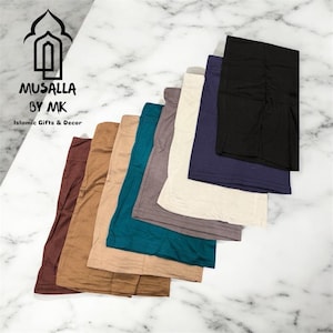 May include: A collection of modest wear skirts in various colors, including brown, tan, teal, gray, off-white, navy, and black. The skirts are arranged in a fan shape, with the brand name "MUSALLA BY MK" and the text "Islamic Gifts & Decor" visible.