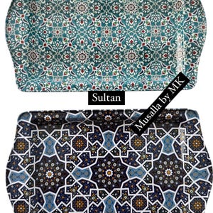 May include: Two decorative trays with intricate geometric patterns. The top tray has a teal background with red and white accents. The bottom tray has a black background with blue, white, and gold accents. The text "Sultan" is below the top tray and "Zeynep" is below the bottom tray. The text "Musalla by MK" is on the right side of the image.