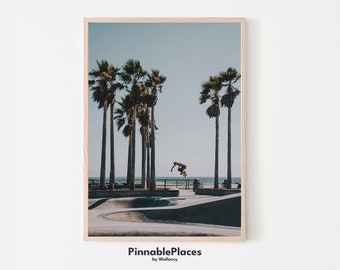 May include: A photograph of a skateboarder performing a trick in a skate park with palm trees in the background. The skate park is located near the beach and the ocean is visible in the distance.