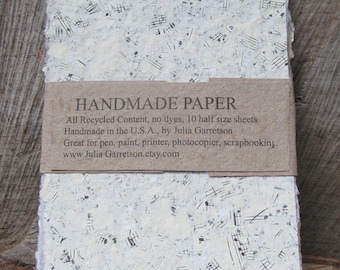 Könnte beinhalten: Handgemachtes Papier mit weißem Hintergrund und schwarzen Noten. Das Papier besteht aus recyceltem Material und ist ideal für Stift, Farbe, Drucker, Kopierer und Scrapbooking. Das Papier wird in den USA von Julia Garretson handgefertigt. Das Papier ist in 10 Blättern im halben Format erhältlich.