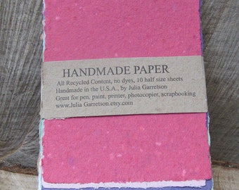 Puede incluir: Una pila de 10 hojas de papel hecho a mano en varios colores pastel, incluyendo rosa, morado, azul, verde y amarillo. El papel está hecho de materiales reciclados y es ideal para bolígrafo, pintura, impresora, fotocopiadora y scrapbooking. "HANDMADE PAPER" está impreso en una etiqueta marrón pegada a la hoja superior. "All Recycled Content, no dyes, 10 half size sheets Handmade in the U.S.A., by Julia Garretson Great for pen, paint, printer, photocopier, scrapbooking www.Julia Garretson.etsy.com" está impreso en la etiqueta.