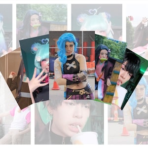 May include: A collage of images featuring cosplayers in various costumes. The central image showcases a cosplayer dressed as Jinx from League of Legends, with blue hair and a black top. Other images include characters from anime and other games.