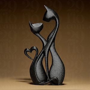 May include: A black cat sculpture with a heart-shaped tail. The sculpture features two stylized cats intertwined, with one cat's head resting against the other. The sculpture is made of a textured material and stands on a neutral surface.