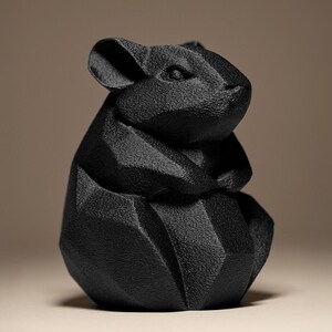 May include: A black, geometric sculpture of a mouse. The sculpture has a textured surface and is made up of angular planes, giving it a modern, abstract appearance. The mouse is depicted in a seated position, with its ears perked up.
