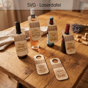 Op de afbeelding: Zes lichtgekleurde houten flessenhangers met lasergegraveerde Duitse tekst en decoratieve patronen. Vier hangers hangen aan glazen flessen in verschillende kleuren, terwijl twee hangers plat liggen. De tekst bevat onder andere Mama HELDIN en Alles Liebe.