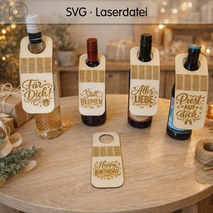 Könnte beinhalten: Wein-Flaschenanhänger aus Holz mit dekorativem Text und Kordel-Akzenten. Die Anhänger enthalten Sätze wie "Für Dich!", "Statt Blumen", "Alles Liebe", "Prost auf dich" und "Happy Birthday".