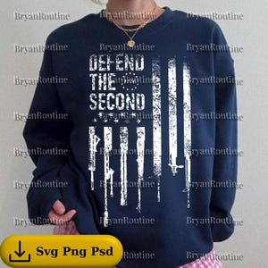May include: Navy blue sweatshirt with a distressed American flag design and the text "DEFEND THE SECOND". The flag incorporates white rifle silhouettes. The sweatshirt has long sleeves and a crew neck.