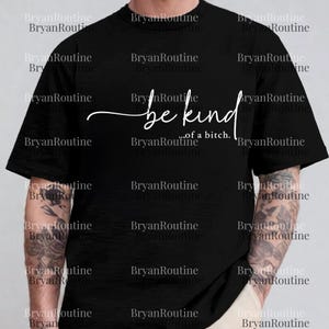 A person wearing a black t-shirt with the text "be kind of aitch" printed on it.