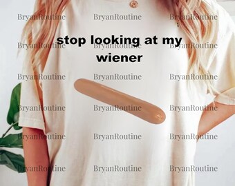 May include: A cream-coloured t-shirt featuring the phrase "stop looking at my wiener" and a cartoon hot dog. The design is simple and the shirt has a relaxed fit.