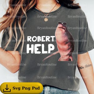 Könnte beinhalten: Dunkelgraues T-Shirt mit einem Grafikdesign einer Kreatur und dem weißen Text "ROBERT HELP". Das Design ist mittig auf dem Shirt platziert. Das T-Shirt hat eine lockere Passform.