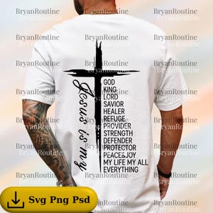 May include: White t-shirt with a black cross design and the words "Jesus is my" on the left side. Below the cross are the words "God, King, Lord, Savior, Healer, Refuge, Provider, Strength, Defender, Protector, Peace & Joy, My Life My All, Everything."