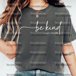 The image is a close-up of a person wearing a gray t-shirt with the text "be kind" printed on it.