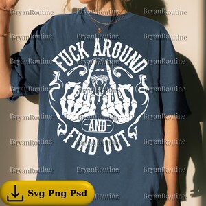 Pode incluir: Camiseta azul marinho com uma estampa branca que diz "FUCK AROUND AND FIND OUT". A estampa inclui mãos de esqueleto e uma cobra. A camiseta tem um corte folgado.