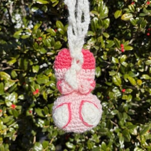 May include: A pink and white crocheted bunny charm with a white crocheted cord.