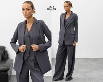 Dreiteiliger Anzug in Dunkelgrau, bestehend aus einer anthrazitfarbenen Hose mit weitem Bein, einer taillierten Weste und einem Blazer, modernem Business-Outfit und einem eleganten Damen-Hosenanzug.