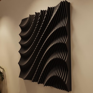 May include: A black, wave-patterned wall art piece. The artwork is composed of layered, curved elements that create a three-dimensional effect. The design is mounted on a wall, showcasing a modern, abstract aesthetic. The piece is a square shape.