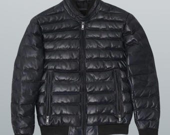 May include: Black leather bomber jacket with a quilted design. The jacket features a zip-up front, two side pockets, and ribbed cuffs and hem. The collar is a stand-up style.