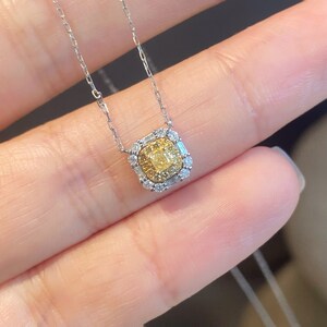 May include: A delicate silver chain necklace with a square pendant featuring a yellow diamond surrounded by smaller diamonds.