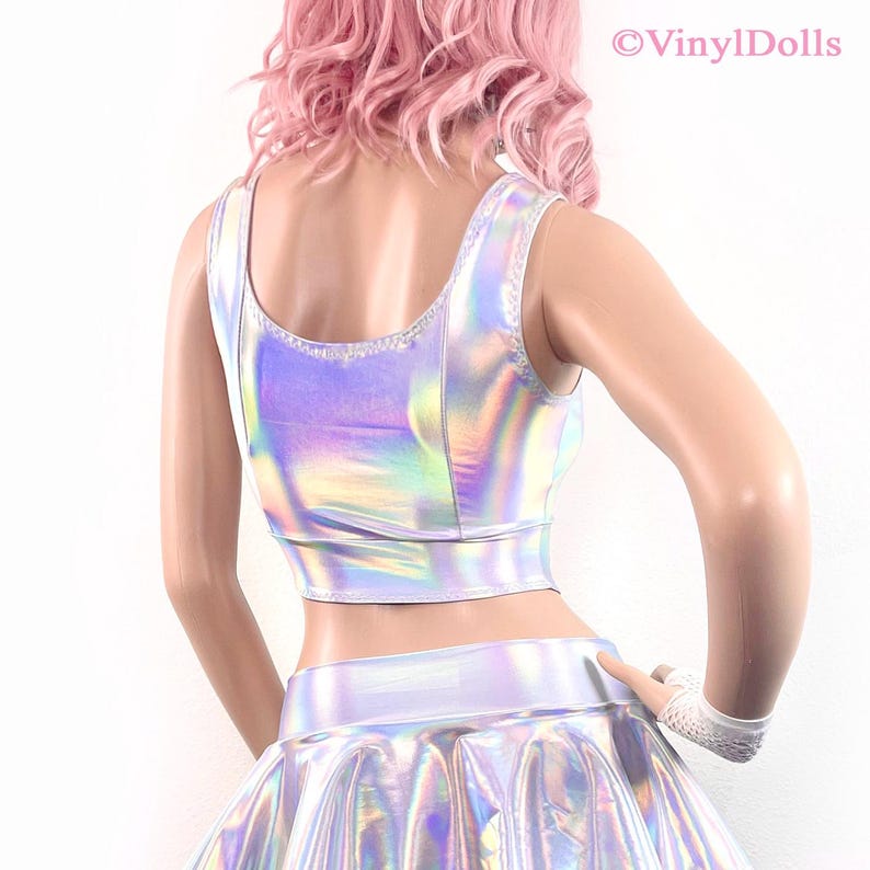 May include: A silver iridescent crop top and skirt set. The top has a scoop neck and sleeveless design. The skirt is a mini skirt with a high waist.