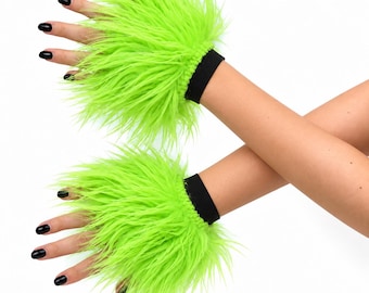 Könnte beinhalten: Ein Paar fingerlose Handschuhe aus langem, leuchtend neongrünem Kunstfell. Die Handschuhe haben ein einfarbiges schwarzes elastisches Bündchen am Handgelenk für einen festen Sitz. Das kräftige grüne Fell bedeckt den Handrücken und die Finger.