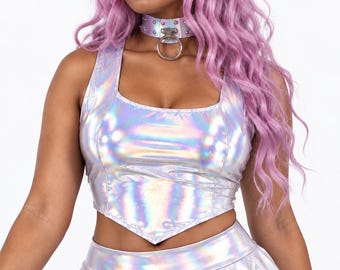 May include: A sleeveless holographic silver crop top with a pointed hemline and a matching holographic silver choker featuring a central metal O-ring and small studs. The garment has a reflective, metallic finish that shifts in color.