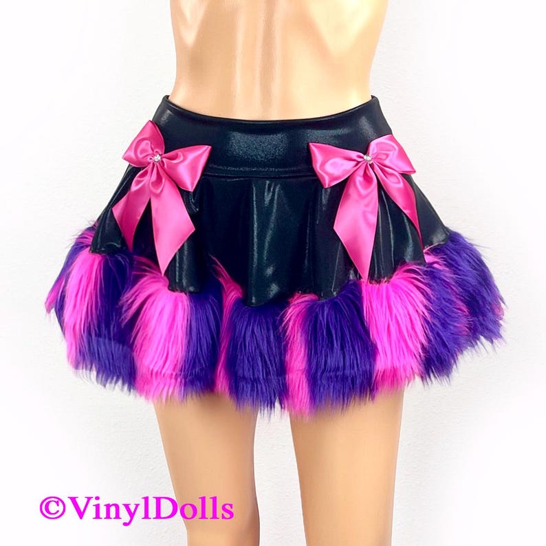 May include: A black mini skirt with a pink and purple faux fur trim. The skirt has two pink satin bows with rhinestones on the front.