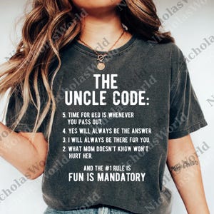 Op de afbeelding: Donkergrijs t-shirt met de witte tekst "THE UNCLE CODE" en een lijst met regels. De regels bevatten uitspraken als "Fun is Mandatory" en "Yes will always be the answer."
