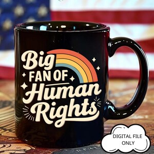 Op de afbeelding: Zwarte keramische mok met de tekst "Big Fan of Human Rights" in een gestileerd lettertype, met een regenboogontwerp. De mok heeft ook de tekst "DIGITAL FILE ONLY" in een witte ovaal. De mok heeft een zwart handvat.