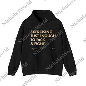 May include: Black hoodie with the text "EXERCISING JUST ENOUGH TO F**K & FIGHT." The hoodie has a front pocket and a hood. The text is in a gold color. The words "Not for passive" and "Fraved" are also on the hoodie.