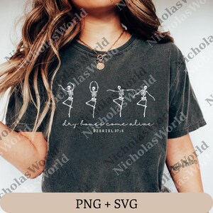 Può includere: T-shirt grigio scuro con grafica bianca di scheletri danzanti. Il testo "dry bones come alive" e "EZEKIEL 37:5" sono stampati sotto. La parte inferiore della maglietta ha il testo "PNG + SVG".
