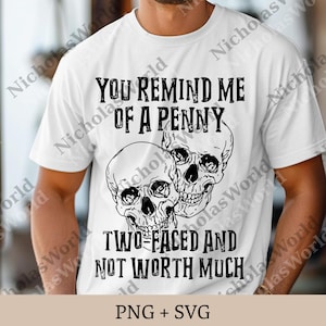May include: White t-shirt with a graphic of two skulls and the text "YOU REMIND ME OF A PENNY TWO-FACED AND NOT WORTH MUCH". The shirt is a crew neck style.