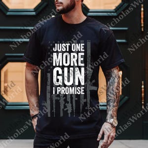 Puede incluir: Camiseta negra con el texto blanco "JUST ONE MORE GUN I PROMISE". El diseño incluye una bandera estadounidense estilizada con siluetas de armas. La camiseta es de manga corta.