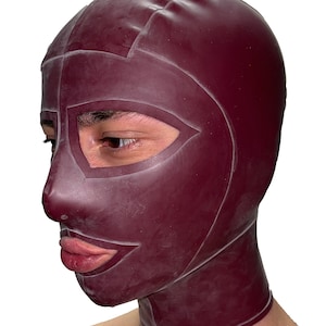 Peut inclure: Un capuchon en latex bordeaux avec un design géométrique. Le capuchon couvre la tête et le cou, avec des ouvertures pour les yeux et une bouche stylisée. Le matériau semble lisse et moulant, avec des coutures visibles. Le fond est blanc uni.