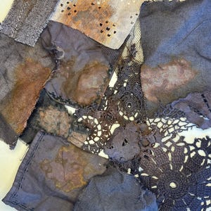 Puede incluir: Un surtido de retales de tela en tonos grises, marrones y morados. Las piezas incluyen textiles tejidos, de ganchillo y perforados, algunos con patrones manchados o desgastados. La disposición sugiere un proyecto de arte textil o una colección de materiales vintage.