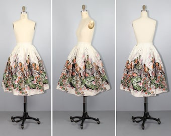 May include: A white full skirt with a colorful print of fruit and vegetables. The skirt is on a dress form.