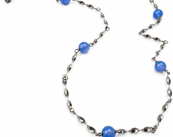 May include: A silver-toned necklace featuring a series of twisted metal links interspersed with vibrant blue spherical beads. The necklace has a delicate, elegant design, perfect for adding a touch of color and sophistication to any outfit.