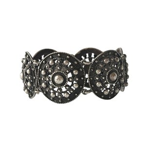 Puede incluir: Un brazalete de plata con un patrón repetido de medallones redondos ornamentados. Cada medallón tiene un centro elevado y un diseño delicado e intrincado.