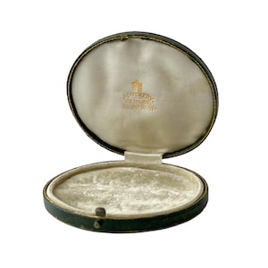 May include: An open, round, green leather jewellery box with a white velvet interior. The box has gold trim and the inscription "W.G.Jenkins 179, Regent St. W."