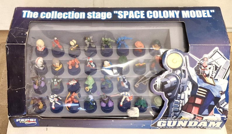 May include: A boxed set of Pepsi Twist bottle cap figures. The box reads "The collection stage SPACE COLONY MODEL" and features a clear window displaying the collection of small, colorful figures. The box also features Gundam artwork.