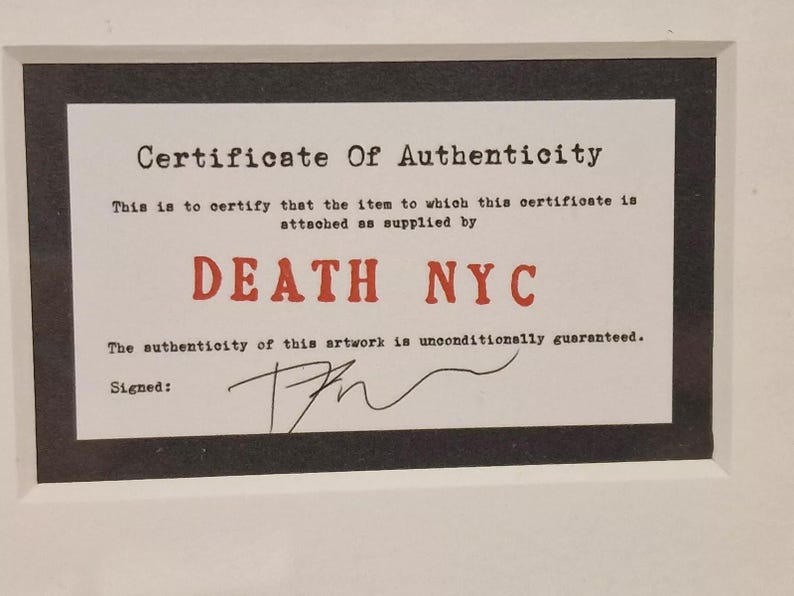 May include: A black and white certificate of authenticity with the text "Certificate of Authenticity" and "DEATH NYC" in red. The text "This is to certify that the item to which this certificate is attached as supplied by" and "The authenticity of this artwork is unconditionally guaranteed." is printed in black. The certificate is signed with a black ink signature.