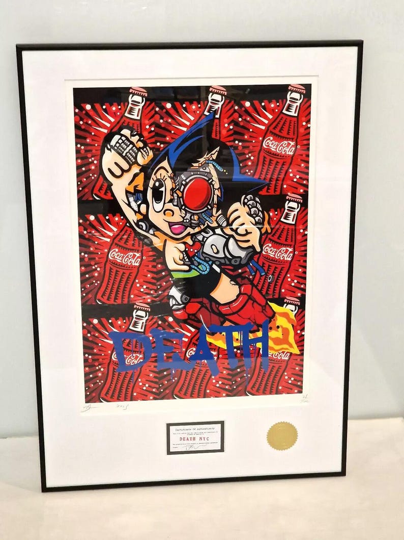 May include: A framed print of a cartoon character with a robotic body, holding a can of Coca-Cola. The character is surrounded by Coca-Cola cans and the word "DEATH" is written in blue paint across the bottom of the print.