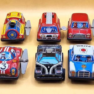 Può includere: Sei auto giocattolo vintage in vari colori, tra cui rosso, giallo e blu. Ogni auto ha una chiave a carica e presenta disegni dettagliati, come strisce da corsa e figure di piloti. Una collezione nostalgica di veicoli giocattolo classici.