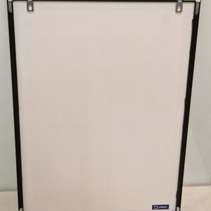 May include: A black picture frame with a white mat and a small blue square with the word "JARSI" printed on it.