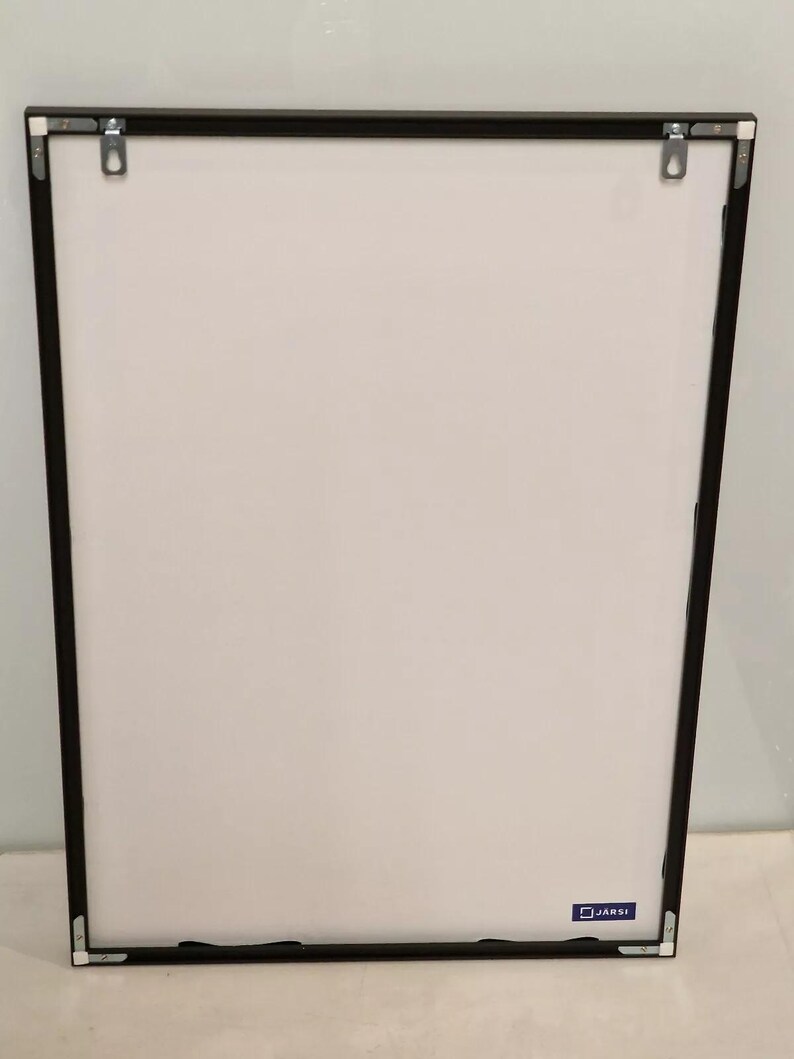 May include: A black picture frame with a white mat and a small blue square with the word "JARSI" printed on it.