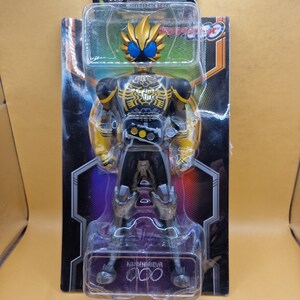 May include: A Kamen Rider OOO action figure in its original packaging. The figure features a black and yellow suit with a gold lion-themed helmet and blue eyes. The packaging includes the text DH SOFVI FIGURE and KAMEN RIDER OOO.
